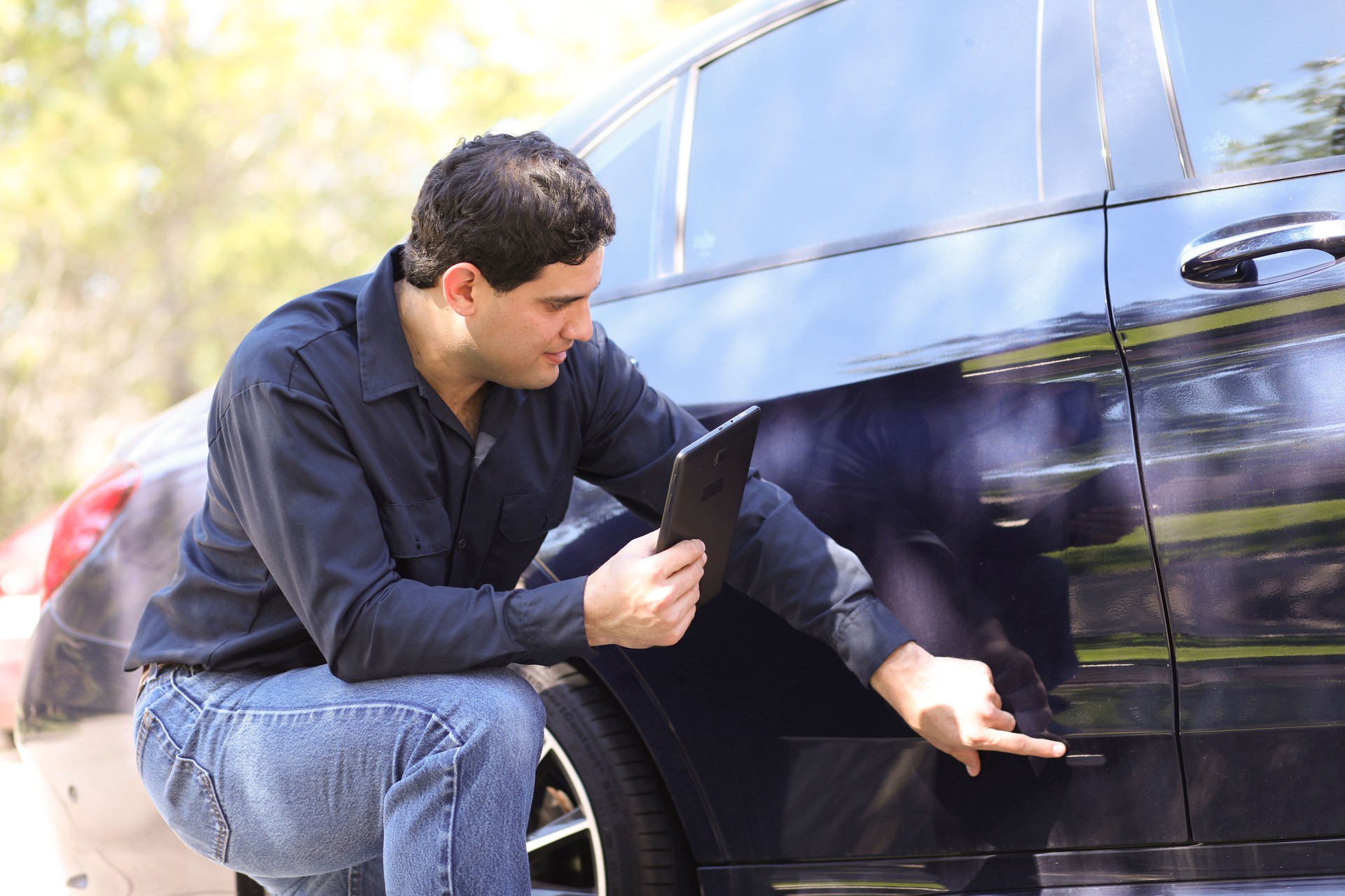 Latin descent man inspects car for damages. Insurance claims.